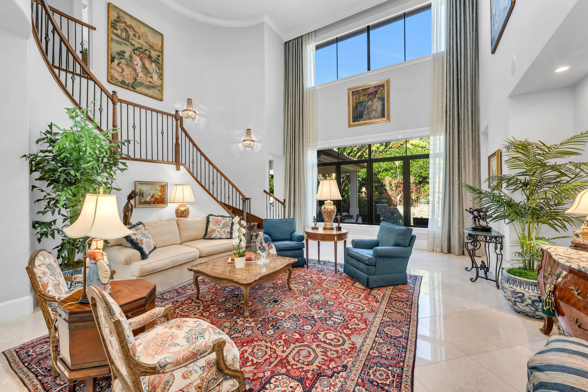 Formal living room has soaring ceilings and light, neutral marble floors.