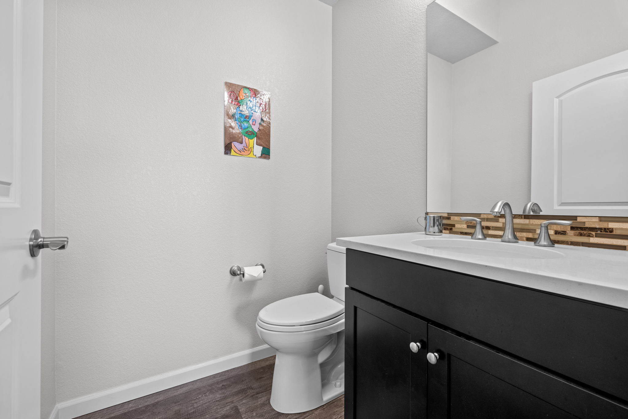 Hallway half bathroom with quartz countertops and stone backsplash
