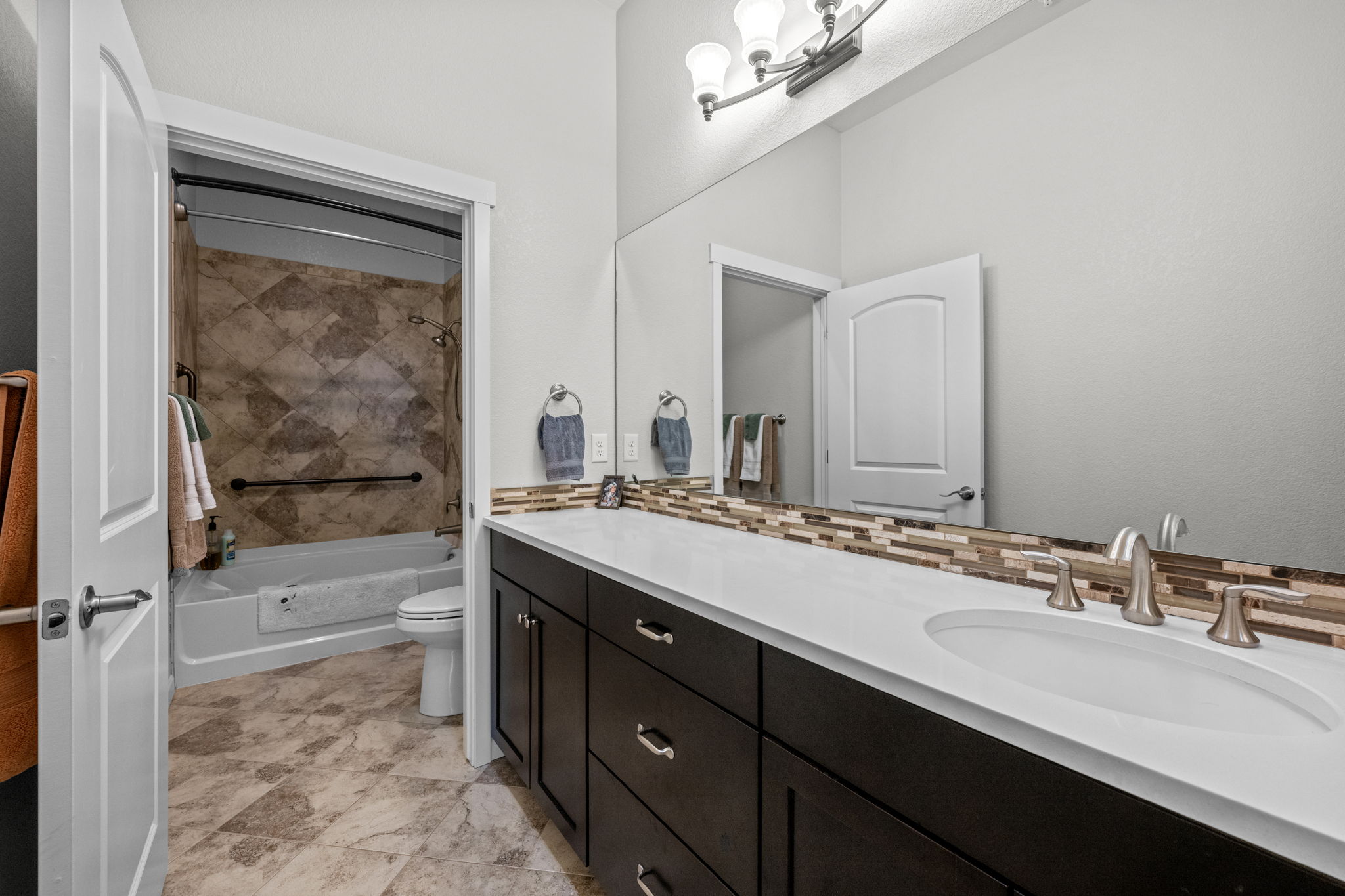 Primary Bathroom with quartz counters, stone backsplash, ceramic tile flooring
