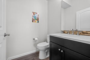 Hallway half bathroom with quartz countertops and stone backsplash