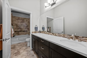 Primary Bathroom with quartz counters, stone backsplash, ceramic tile flooring
