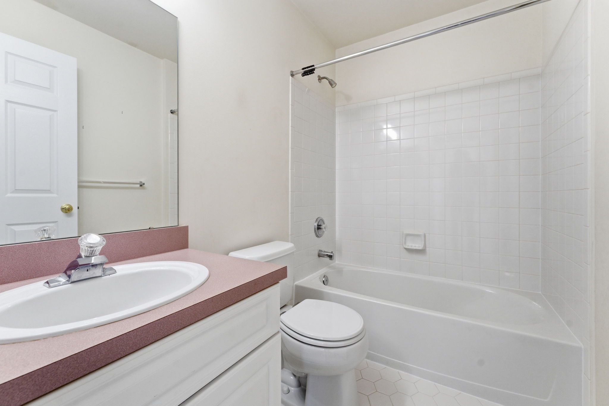 Oval basins in white vanity, tub-shower in tile surround, tile floor.