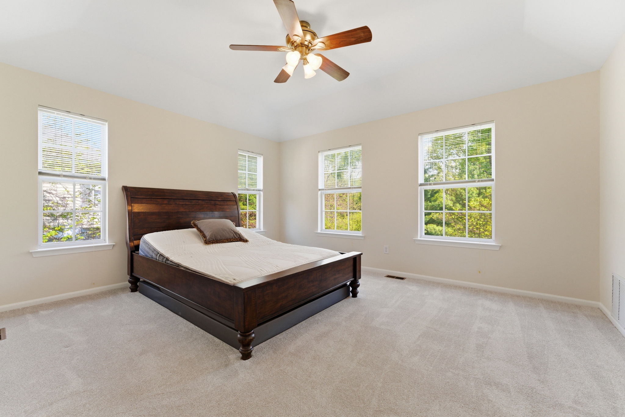 Spacious primary suite features a deep tray ceiling, ceiling fan, a large walk-in closet and newer wall-to-wall carpet.