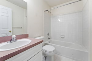 Oval basins in white vanity, tub-shower in tile surround, tile floor.