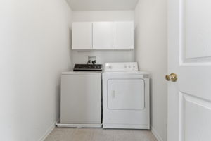 Convenient laundry closet with cabinetry, washer and dryer.
