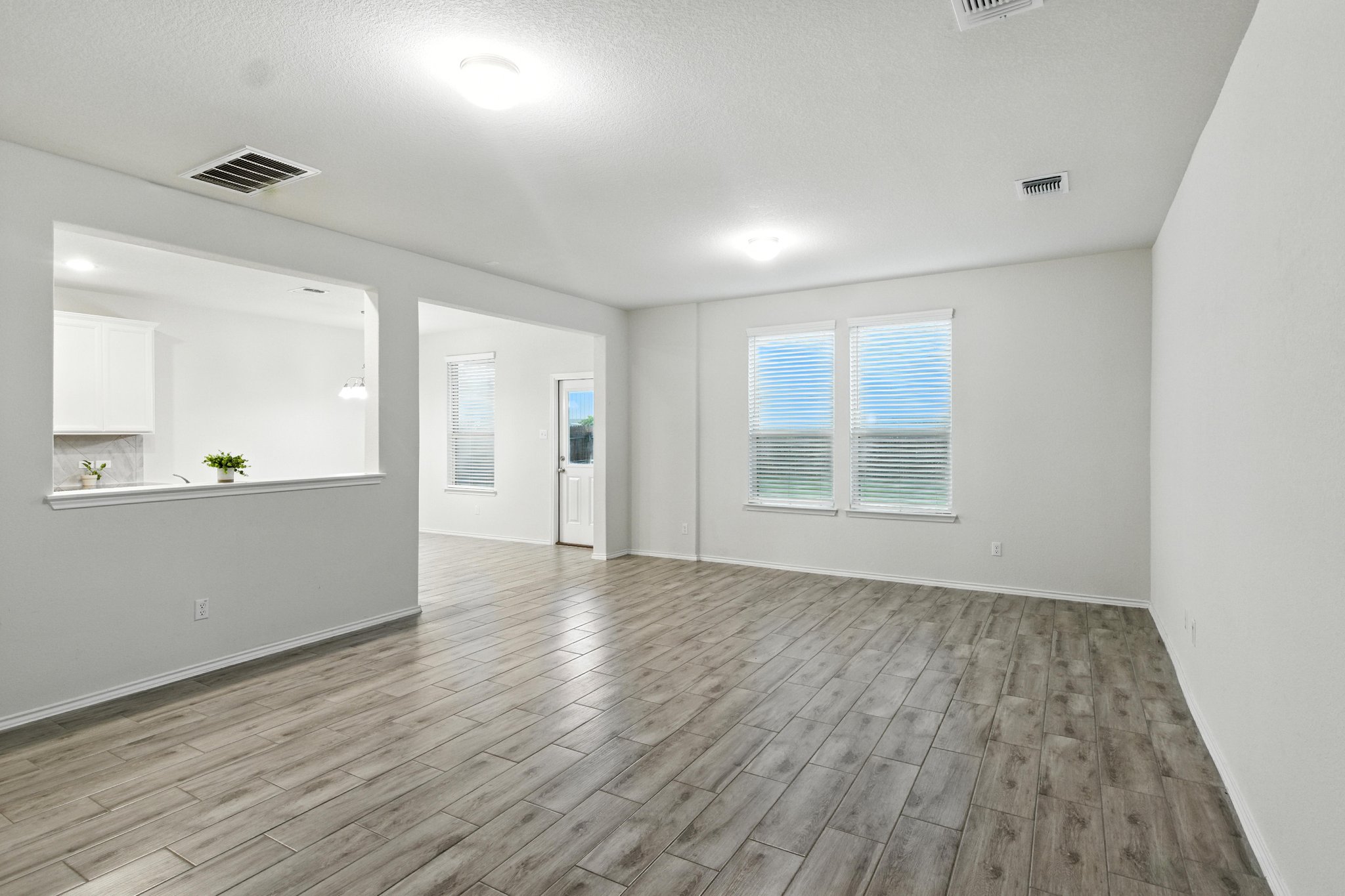The spacious family room features beautiful wood look tile floors and a wall of windows for plenty of natural light.