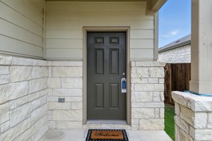 A charming covered porch with stone accents welcome all who enter here.
