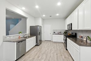 The spacious kitchen features stainless appliances, granite counters and beautiful wood look tile floors.