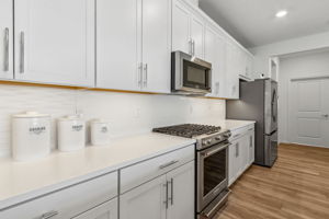 The kitchen features white quartz countertops...