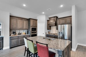 Your gorgeous kitchen is a chef's dream, featuring granite countertops, tasteful backsplash, custom cabinetry with pot and pan drawers, large island, and built-in SS appliances