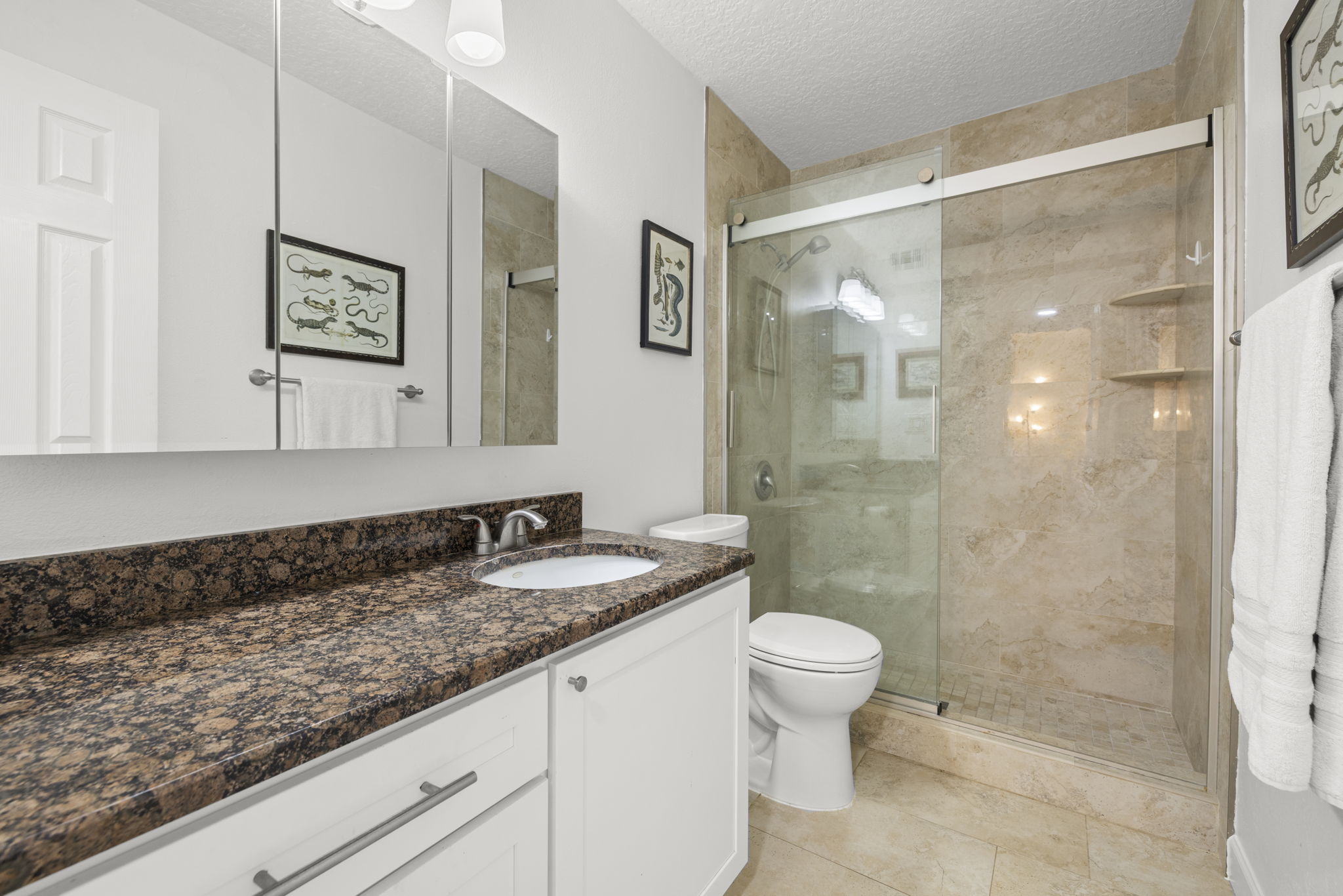 Updated Bathroom with new tile, granite vanity, glass shower door, and modern finishes.