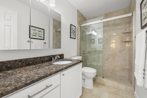 Updated Bathroom with new tile, granite vanity, glass shower door, and modern finishes.