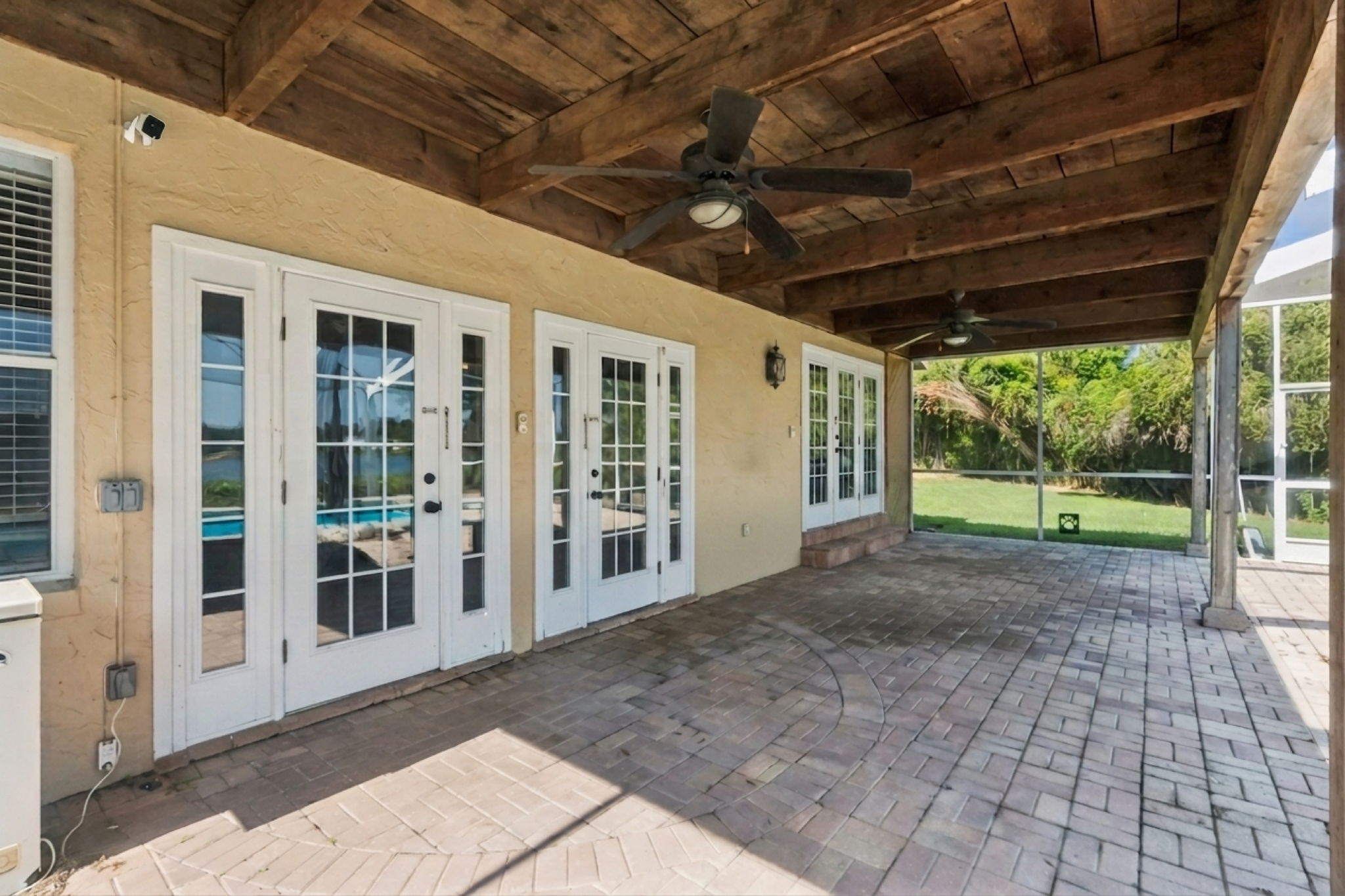 Relaxing covered paver outdoor patio next to the pool with double doors to the family room and the dining room.