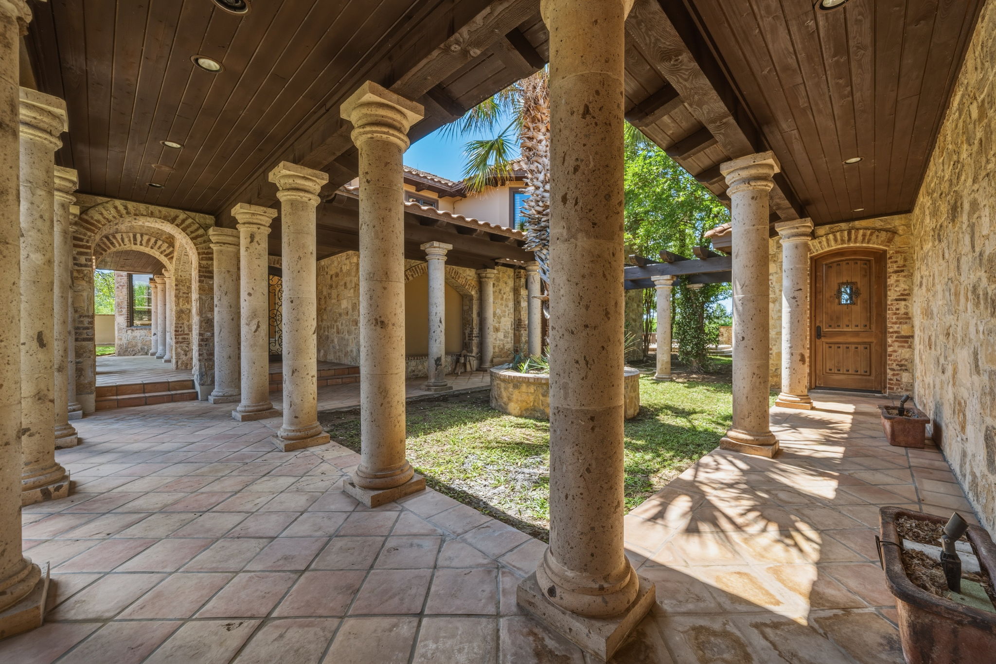 Stone Columns, brick archways, terracotta floor tiles and dark wood ceiling with recessed lighting.