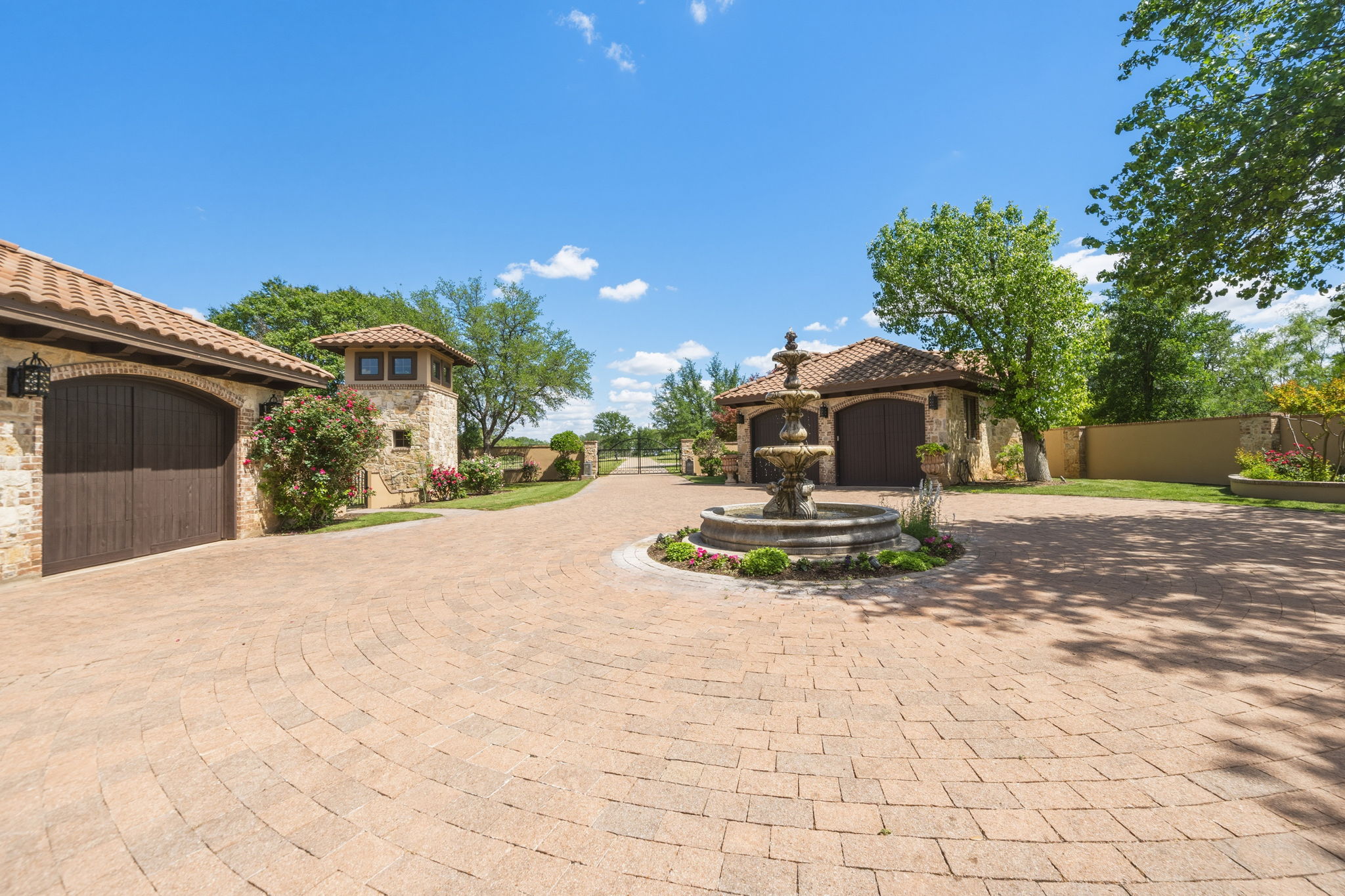 The two detached two-car garages are insulated and dedicated HVAC with arched wooden doors, and a stone facade.