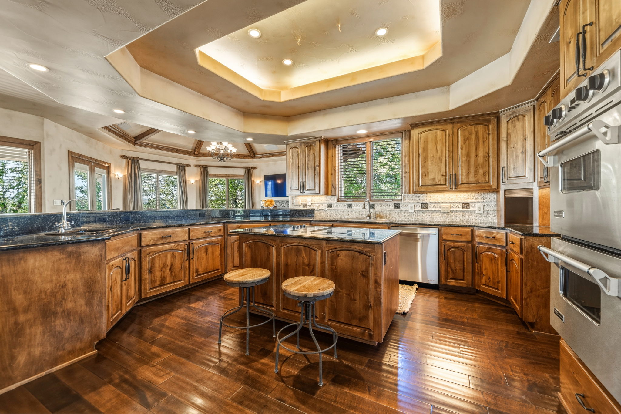 The gourmet kitchen features knotty alder cabinetry, granite countertops, and stainless steel appliances, including double ovens and a refrigerator.