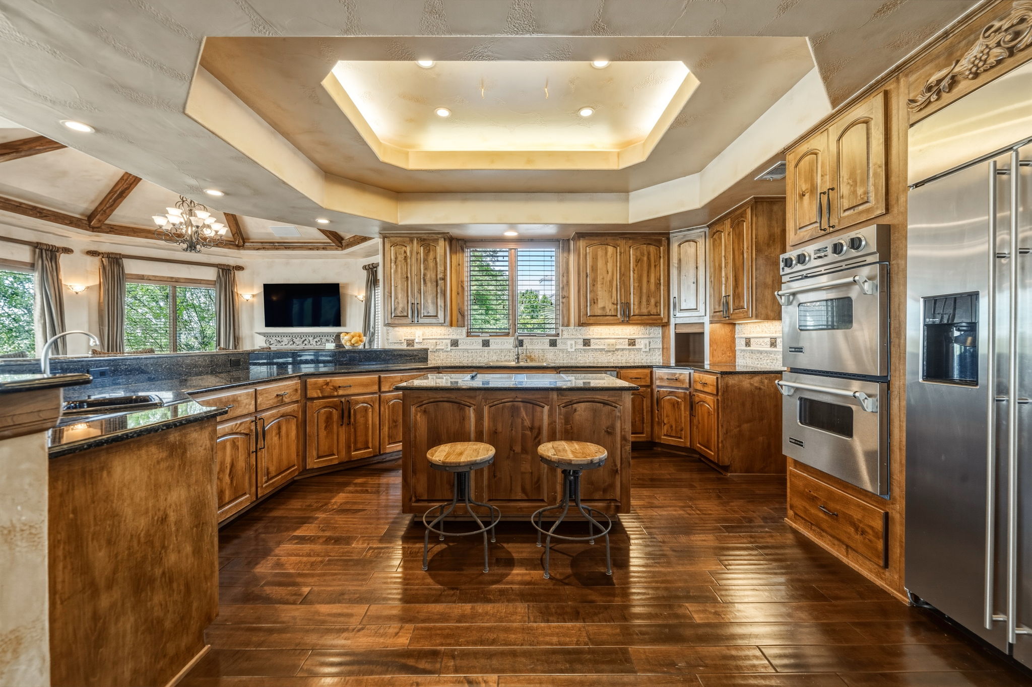 The gourmet kitchen features knotty alder cabinetry, granite countertops, and stainless steel appliances, including double ovens and a refrigerator.