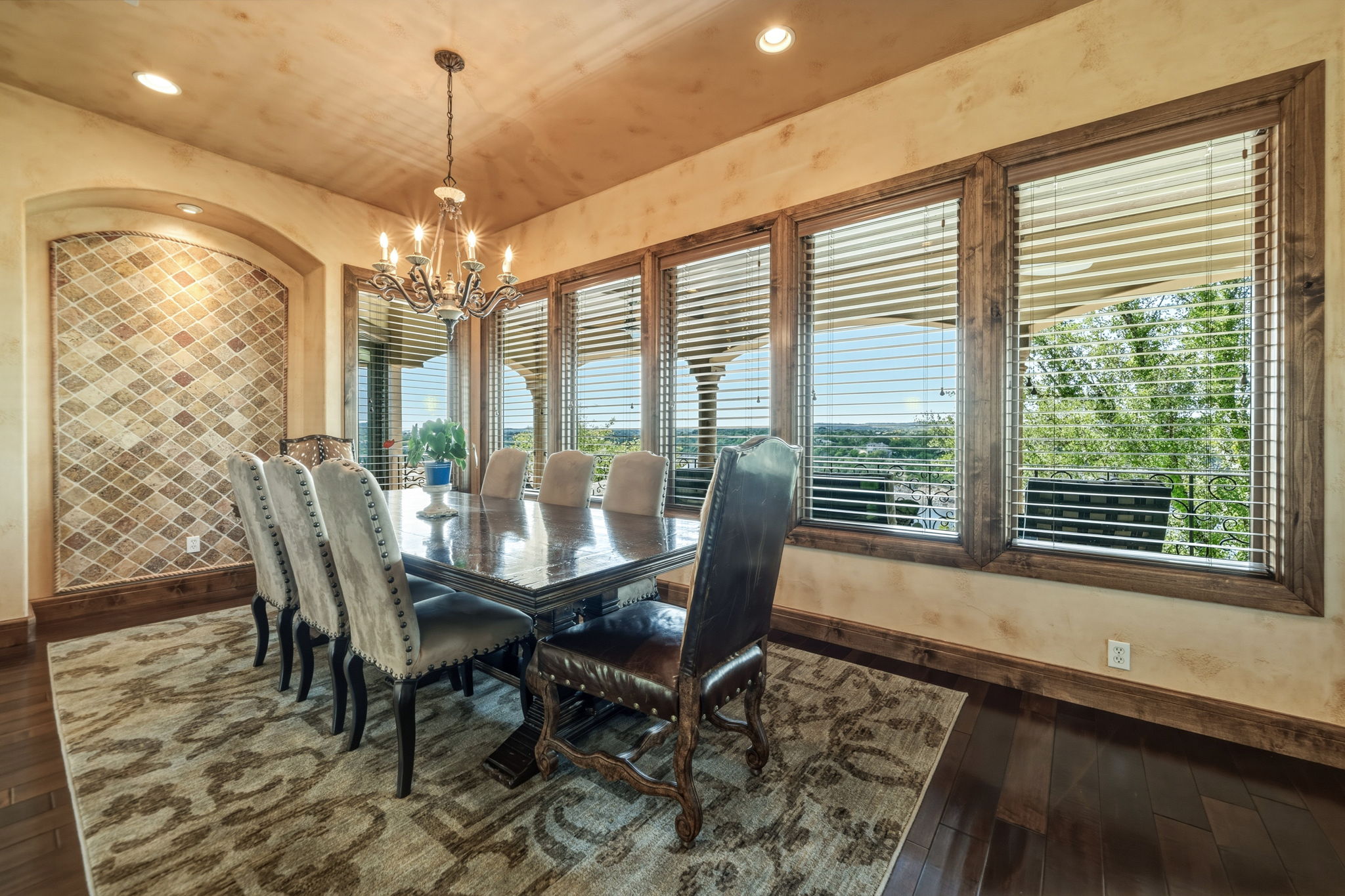 The dining area features views, hardwood floors, a chandelier, and large windows with wooden blinds.