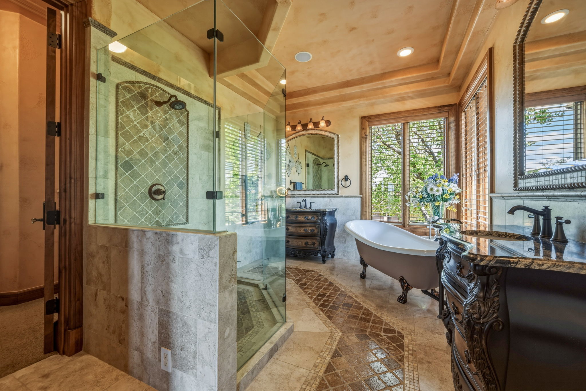 Primary Bathroom features a spacious glass-enclosed shower, a freestanding clawfoot tub, and dual vanity areas with ornate cabinetry and granite countertops.  You also have a large walk in closet and a sizable linen closet.