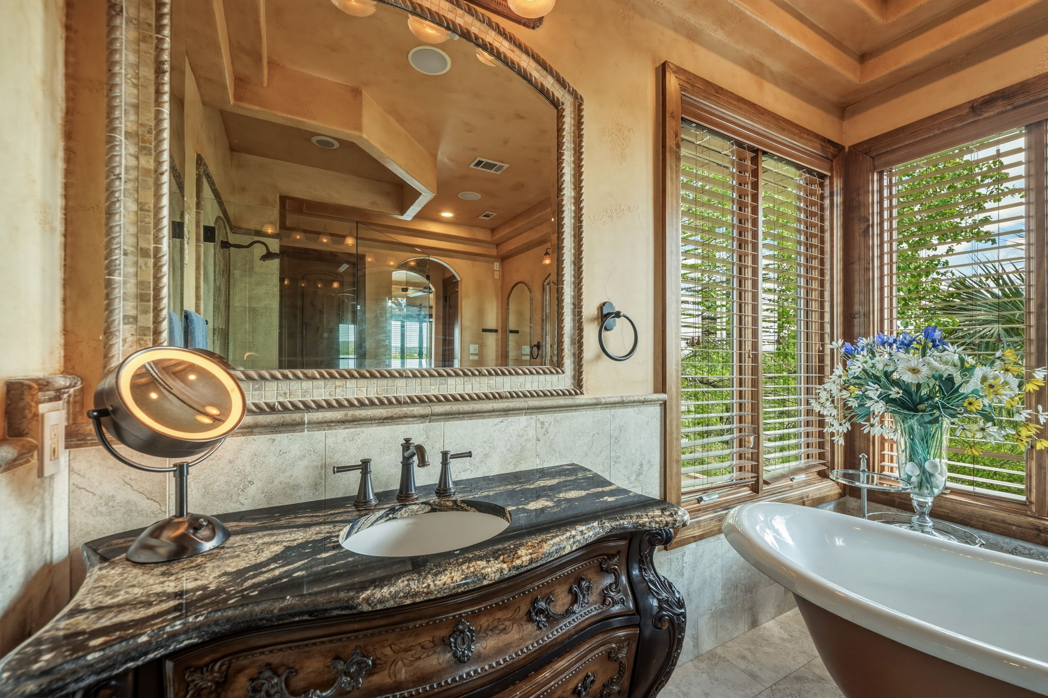 Primary Bathroom features  dual vanity areas with ornate cabinetry and granite countertops.   A freestanding clawfoot tub awaits you.