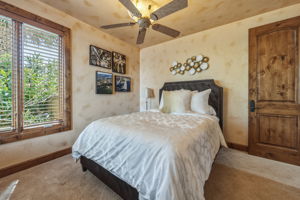 This room features a window with wood blinds, a ceiling fan, and a wood door with an arched top panel.