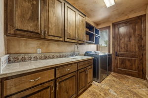 Laundry room consists of a large sink, knotty alder cabinetry and a washer and dryer.