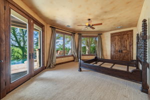 The french doors lead to the swimming area.  The spacious room features broadloom carpeting, a ceiling fan, and large windows with outdoor views.