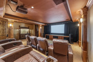 Enjoy your home theater featuring a projector, a large screen, and rows of brown leather recliners.