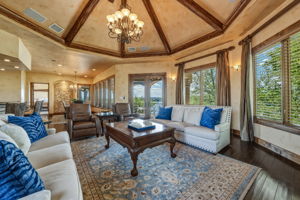 This living area features a dramatic coffered ceiling with exposed wood beams and an ornate chandelier with hill country views.