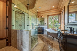 Primary Bathroom features a spacious glass-enclosed shower, a freestanding clawfoot tub, and dual vanity areas with ornate cabinetry and granite countertops.  You also have a large walk in closet and a sizable linen closet.