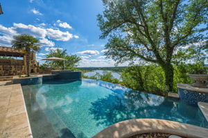 Waterfront views and an infinity-edge pool with a tiled spa and a stone patio.