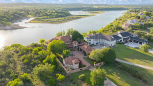 Waterfront views from this Estate home features a gated entrance and a central fountain, set against a backdrop of the hill country.