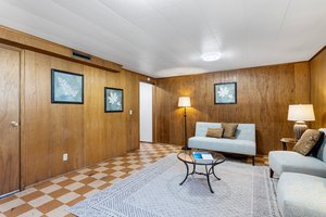 The room features warm tones of real wood paneling. A wonderful place for a theater or entertainment center.