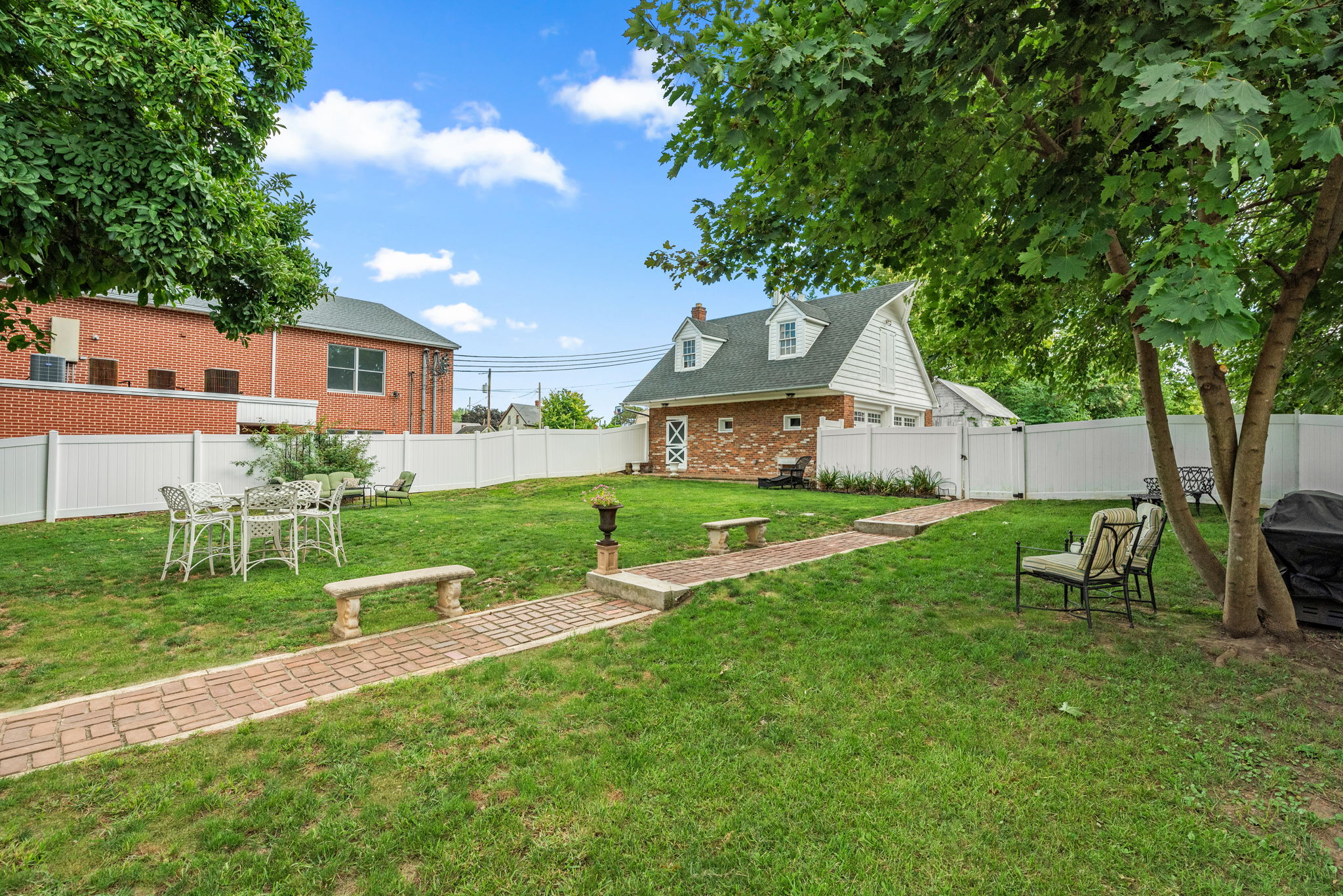 Lawn leading to parking beyond the fully fenced yard and carriage house.