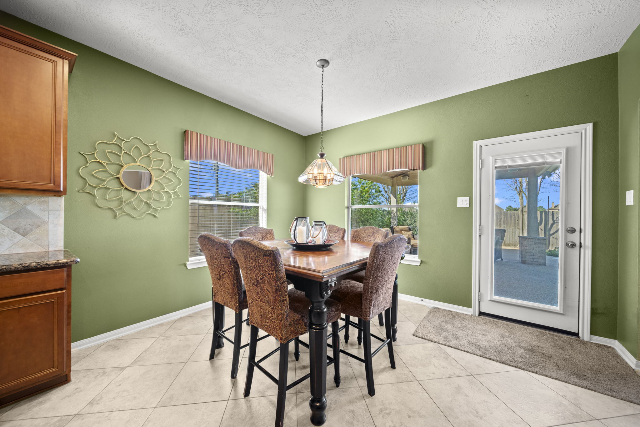 Breakfast area with tile flooring, a chandelier, 2" blinds a view of your backyard oasis!