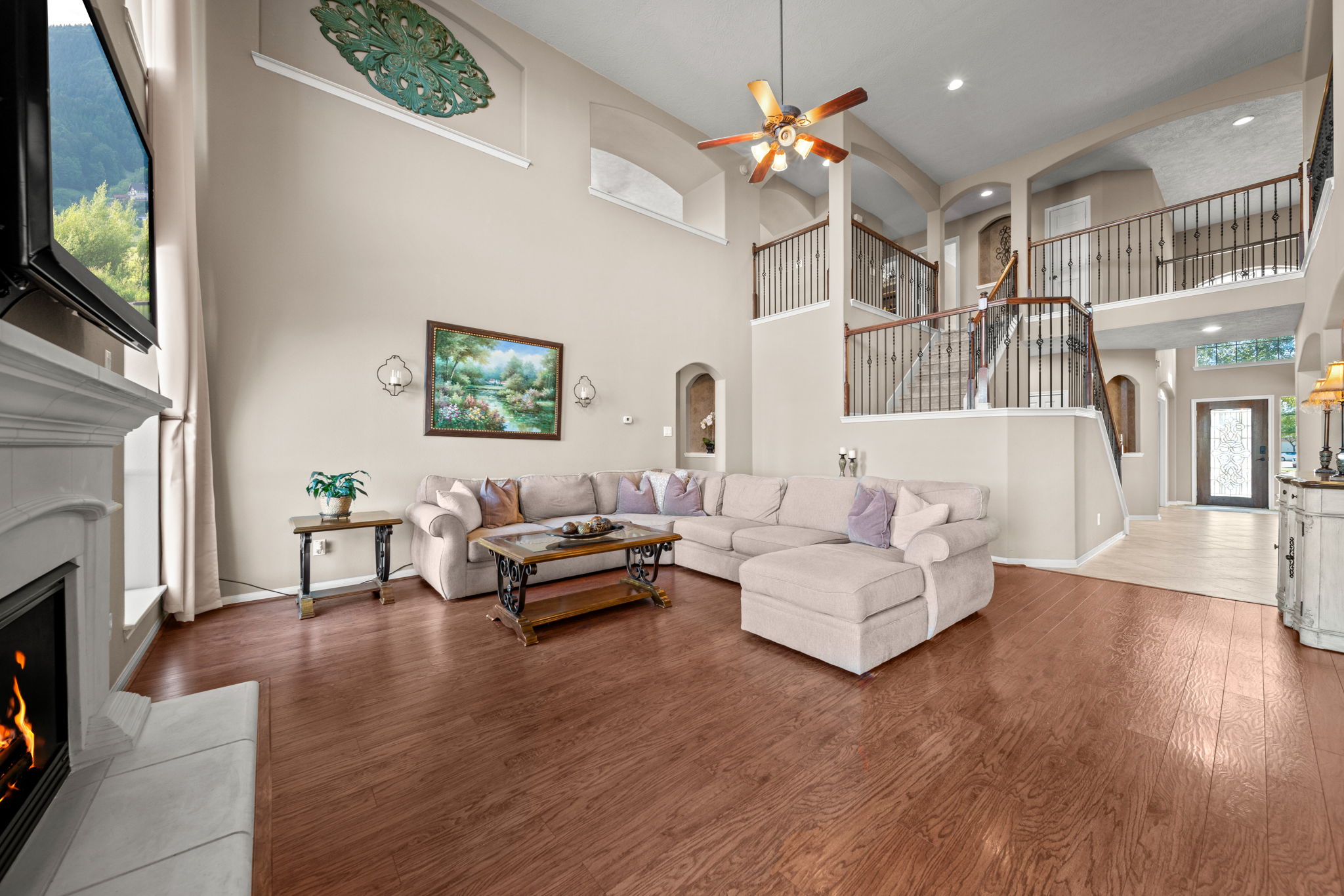 Living room with soaring ceilings, laminate flooring, art niches and a beautiful view of the wrought iron detail on this J.Patrick Homes stairway.