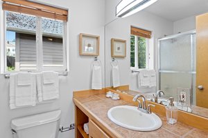 The primary bathroom features a window, a tile countertop with a vanity, and lots of cabinet space to keep your essentials organized. The updated lighting enhances the style and comfort of this space.