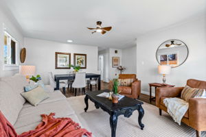 This living room is so well lit naturally and connects to the primary bedroom, bathrooms, and laundry through the hallway you see at the back of the photo.