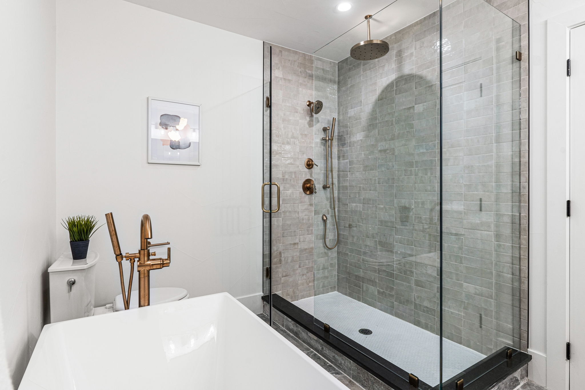 The spacious walk-in shower features a glass surround, large rain head, and handheld shower head