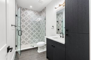 Sizable extra bathroom with frameless, glass shower door and decorative tile.