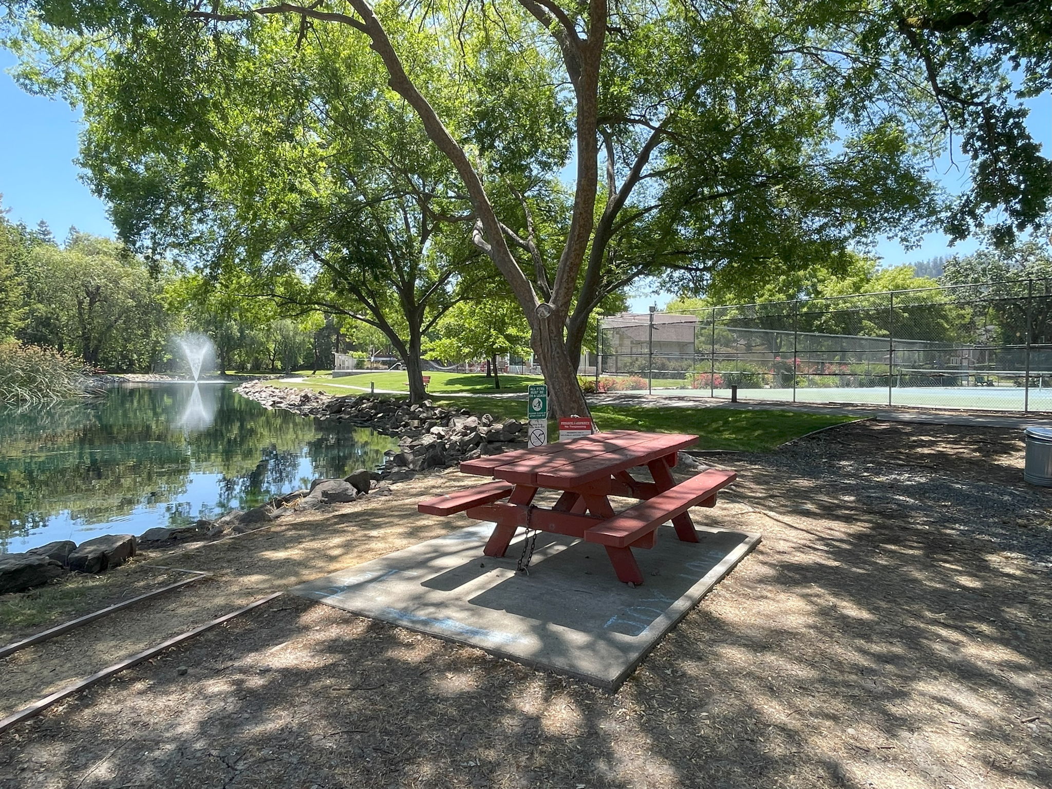 Picnic table near tennis courts, lagoon and walking path