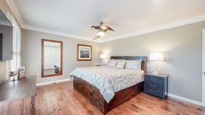 Another attractive bedroom with wood floors and a unique ceiling fan.