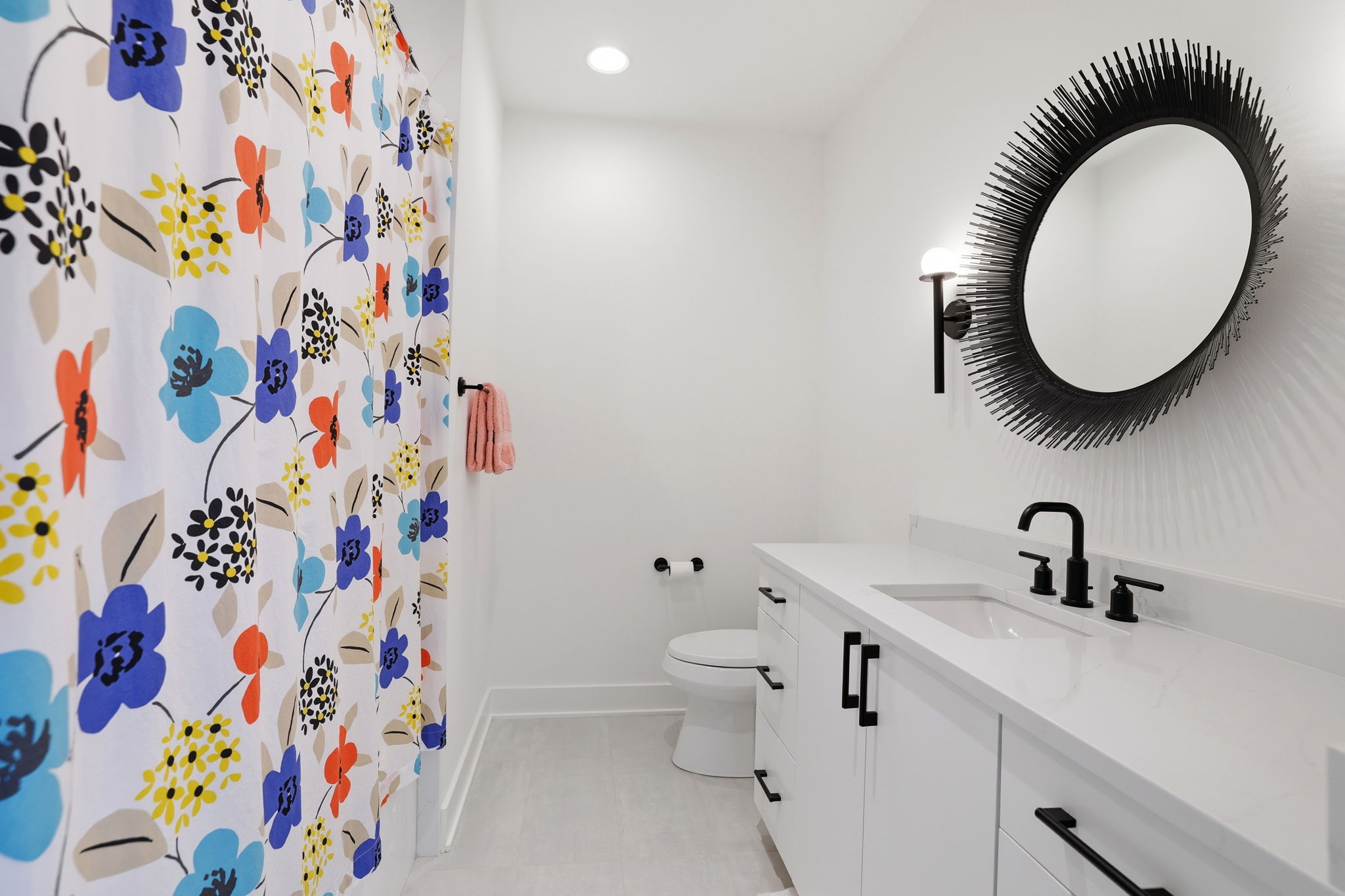 A stylish en-suite bath featuring statement lighting and a striking designer mirror