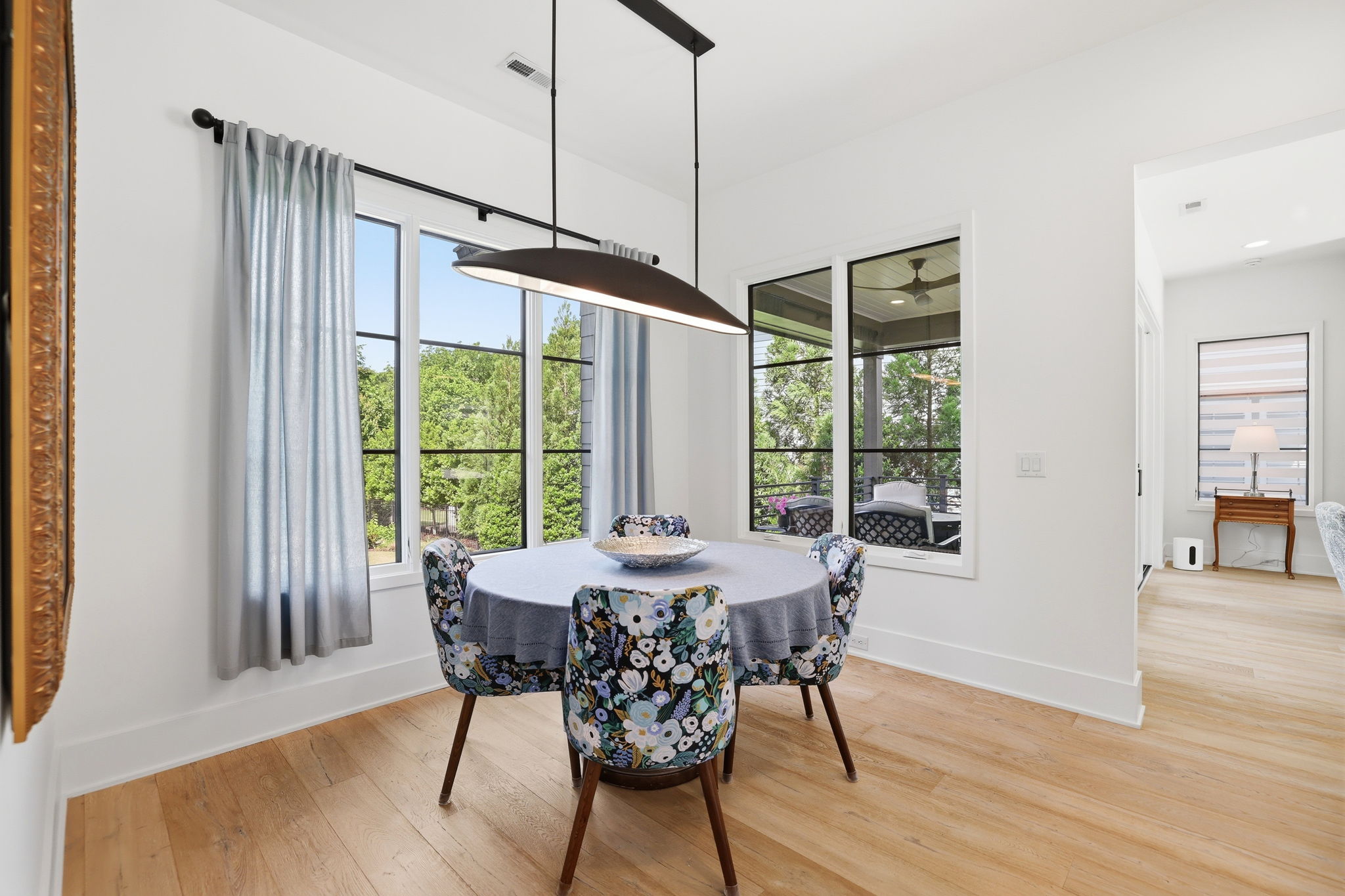 Charming dining area with serene outdoor views, highlighted by statement designer lighting