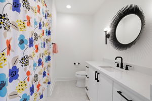 A stylish en-suite bath featuring statement lighting and a striking designer mirror