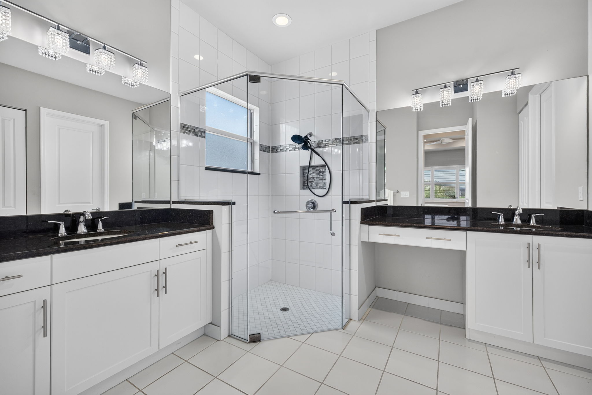 Seamless shower door, floor to ceiling tile and corner seat in shower, upgraded lighting, too! Vanity area and dual sinks. Grab bar present in shower. Lots of storage!
