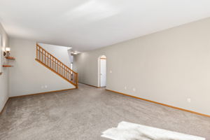 Looking from fireplace wall, showing stairs to second floor and arched opening to primary suite.