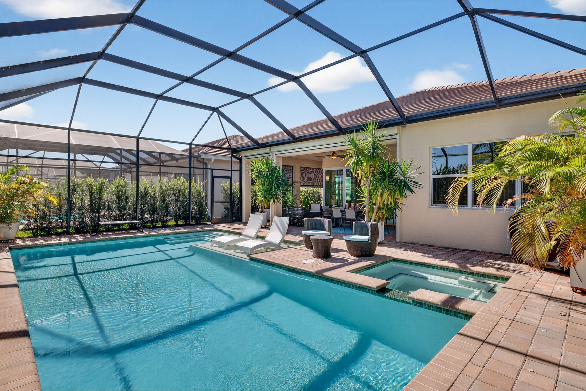 This pool area has it ALL! A heated, saltwater pool w/ sun shelf, attached hot tub, lush privacy landscaping, views of the lake and butterfly garden, and a shaded seating area off great room!