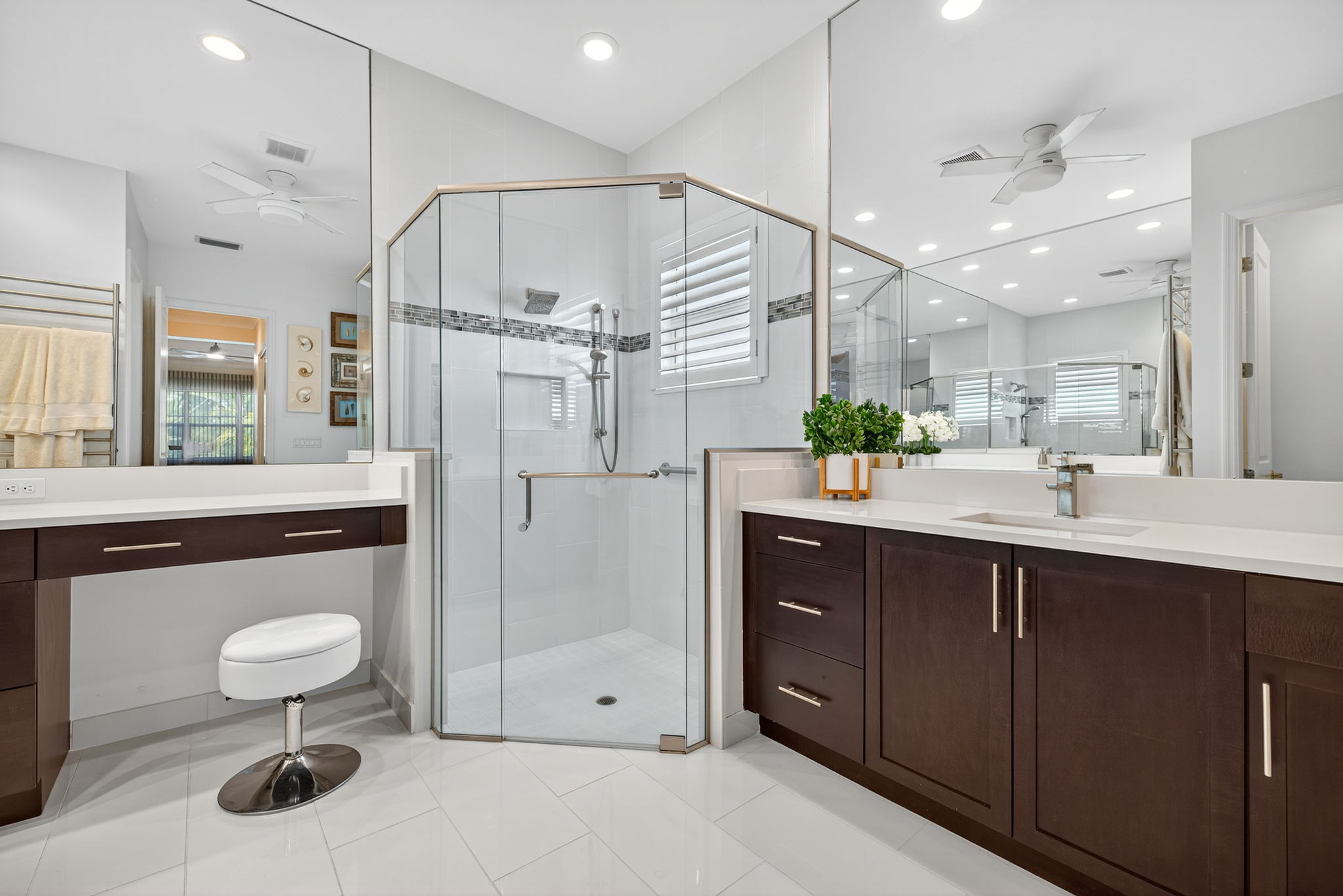 Seamless shower door, listello tile accent border in shower, a ceiling fan and large drawers make this primary bath a winner!