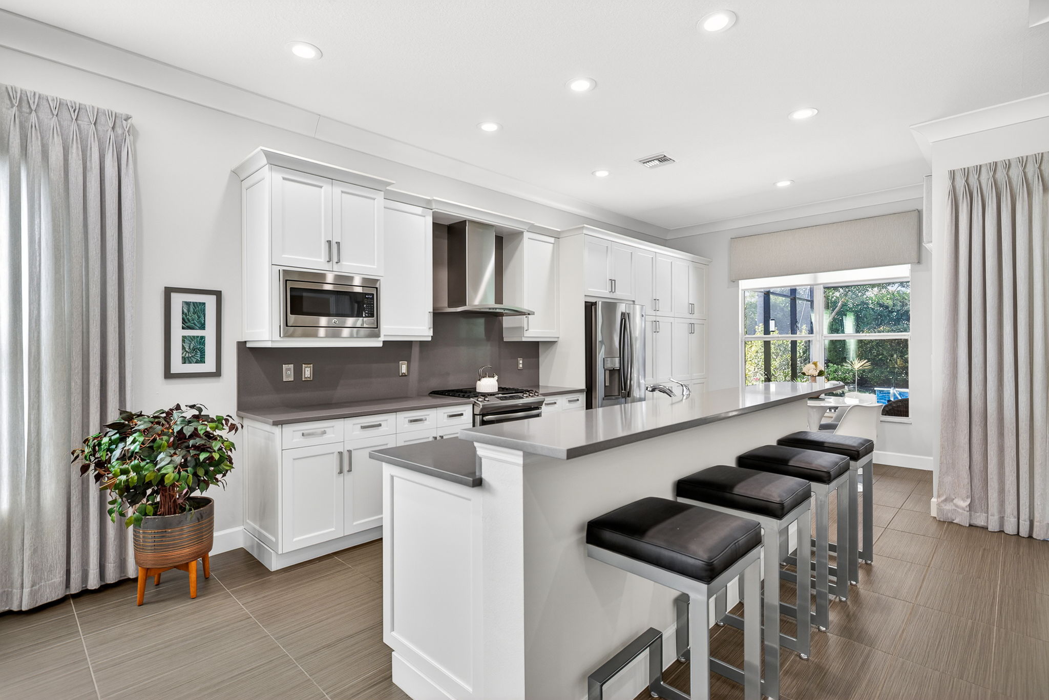 Chimney hood, bar seating for 4, soft-close cabinets, slide-out shelves in extended cabinetry to right of counter-depth fridge, quartz counters and backsplash, slide-in range, above and below cabinet lighting.